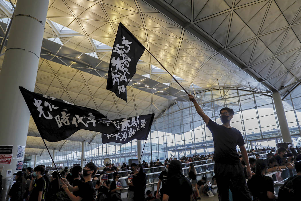 Protesters wave flags at the Hong Kong International Airport, Monday, Aug. 12, 2019. One of the ...