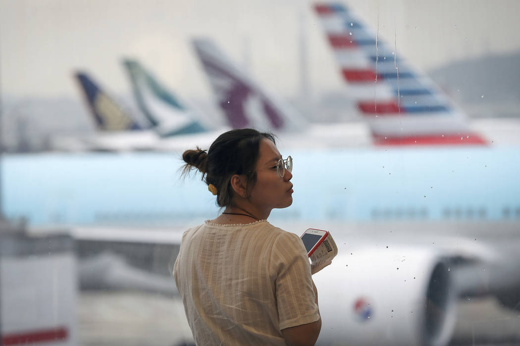A woman reacts as airplanes are parked at the Hong Kong International Airport, Monday, Aug. 12, ...