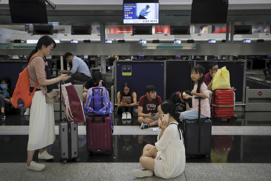Travelers gather at the closed check-in counters as protesters stage a protest at the Hong Kong ...