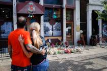 Mourners pause at a makeshift memorial for the slain and injured outside Ned Peppers bar in the ...