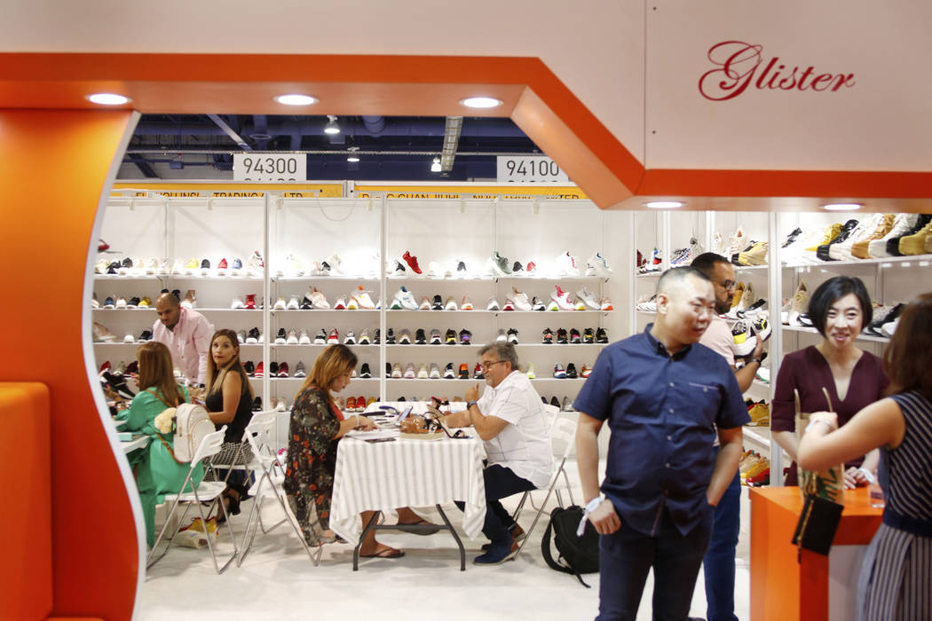 Consumers speak with exhibitor Elite Footwear during the first day of the MAGIC trade show at t ...