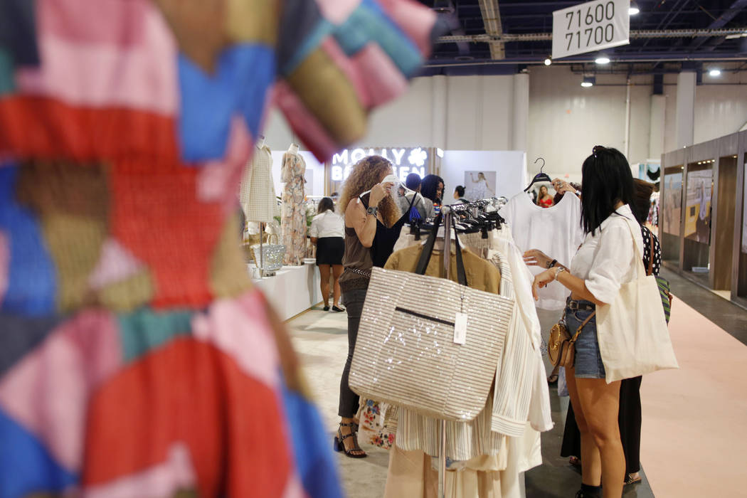 Attendees look at Molly Bracken collections on the show floor during the first day of the MAGIC ...
