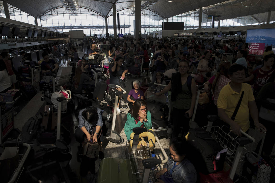 A beam of sunlight is cast on the travelers as they wait at the check-in counters in the depart ...