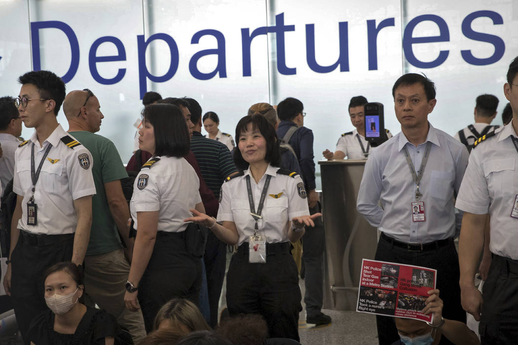 An airport security staff member gestures to travelers at the Hong Kong International Airport i ...