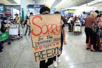 A protester shows a placard to stranded travelers during a demonstration at the Airport in Hong ...