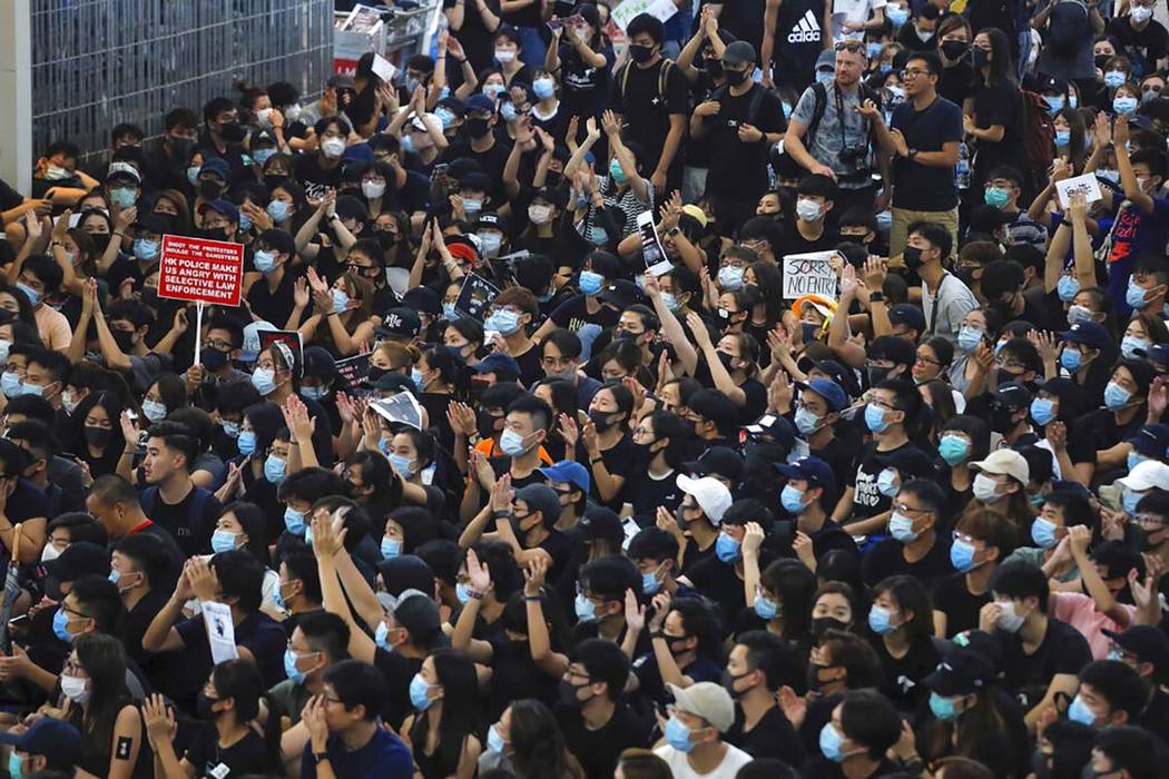 Protesters gesture as they stage a sit-in rally at the Airport in Hong Kong, Tuesday, Aug. 13, ...