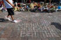 A pedestrian passes a makeshift memorial for the slain and injured victims of a mass shooting t ...
