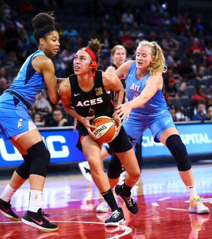 Las Vegas Aces' Dearica Hamby, center, looks to shoot under pressure from Atlanta Dream's Nia C ...