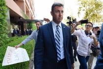 U.S. Rep. Duncan Hunter, center, leaves an arraignment hearing as a protester carries a sign, l ...