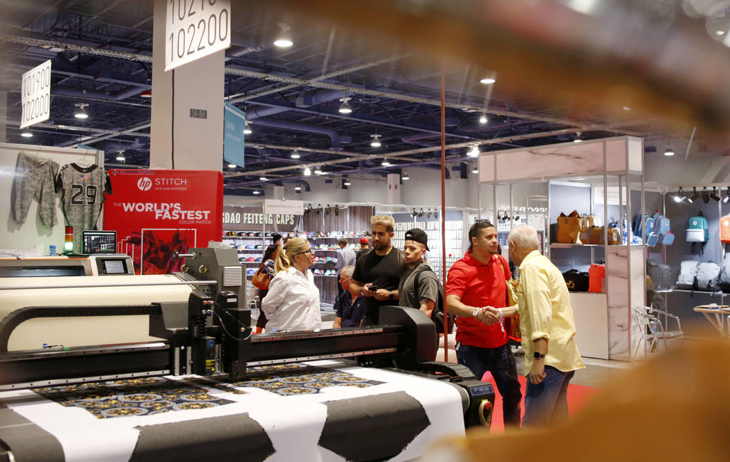 Individuals look at the Hp Stitch dye-sub printing process during the second day of the MAGIC t ...