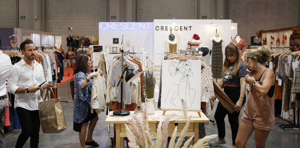 Individuals visit Crescent's exhibit during the second day of the MAGIC trade show at the Las V ...