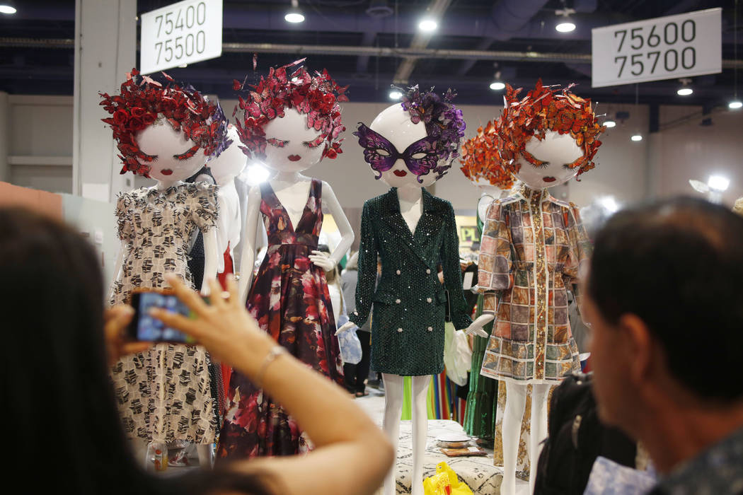 Attendees take a photo of the INA display on the floor during the second day of the MAGIC trade ...