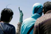 FILE - In this May 7, 2015, file photo, people look at the Statue of Liberty from a ferry boat ...