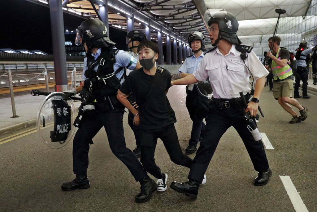 Policemen arrest a protester during a clash at the Airport in Hong Kong, Tuesday, Aug. 13, 2019 ...