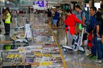 Travellers look at placards and posters placed by protesters at the airport in Hong Kong, Wedne ...