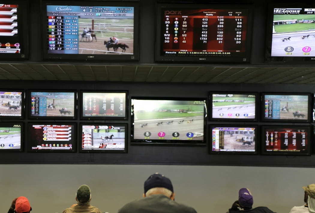FILE - In this May 14, 2018, file photo, men watch horse racing on an array of screens at Monmo ...