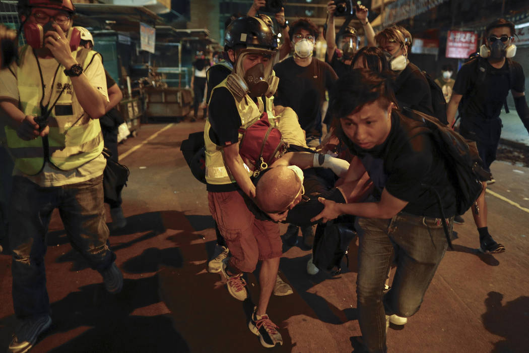 Medical staff and protesters carry an injured man as they face off with policemen near the Shum ...