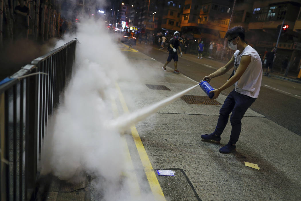 A man uses a fire extinguisher to put out a tear gas canister as they confront police in Hong K ...