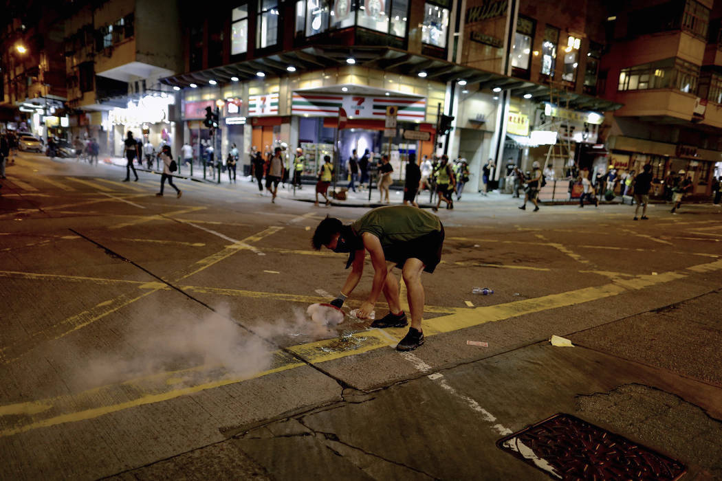 A protester uses a plate to cover a tear gas during clashes with policemen near the Shum Shui P ...