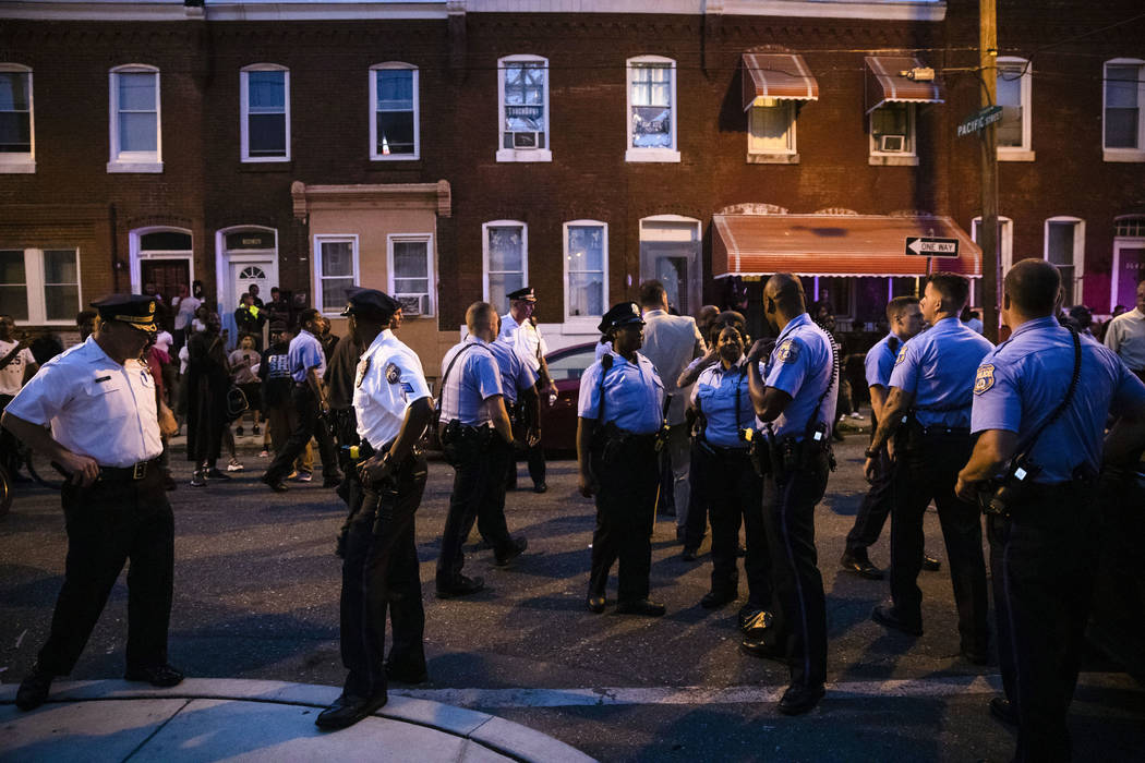 Officers gather for crowd control near a massive police presence set up outside a house as they ...