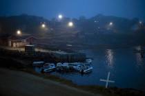 A cross sits on the side of the road as fog covers homes in Kulusuk, Greenland, early Thursday, ...