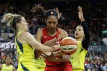 Las Vegas Aces' A'ja Wilson, center, fights for a loose ball with Seattle Storm's Sami Whitcomb ...