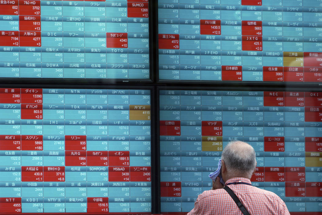 A man looks at an electronic stock board showing Japan's Nikkei 225 index at a securities firm ...