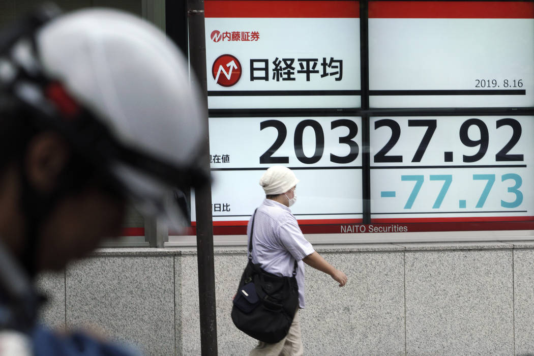 A man walks past an electronic stock board showing Japan's Nikkei 225 index at a securities fir ...