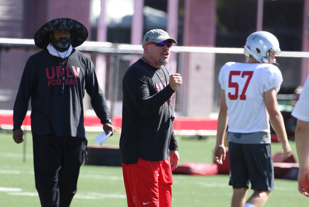 UNLV Rebels head coach Tony Sanchez, center, instructs his players during team practice as Sean ...