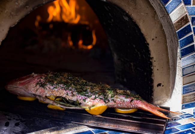 A red snapper cooks in a pizza oven in the backyard of John Courtney, chef of Block 16 at The C ...