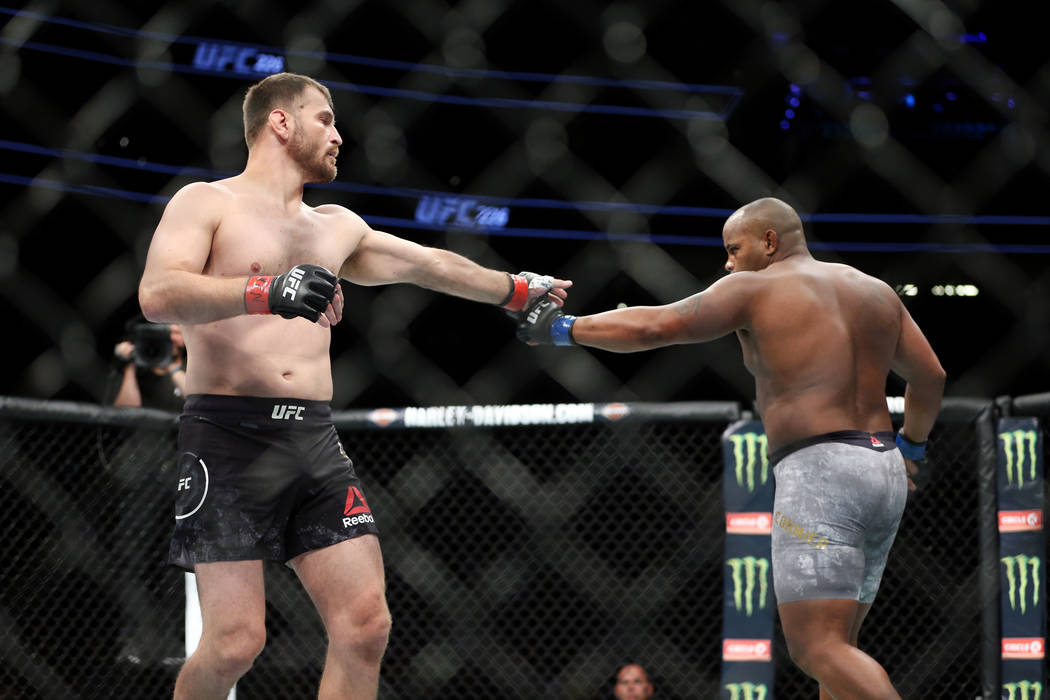 Stipe Miocic, left, and Daniel Cormier touch gloves at the beginning of the heavyweight title b ...