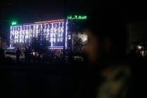 Afghan police men stand guard outside the wedding hall after an explosion in Kabul, Afghanistan ...