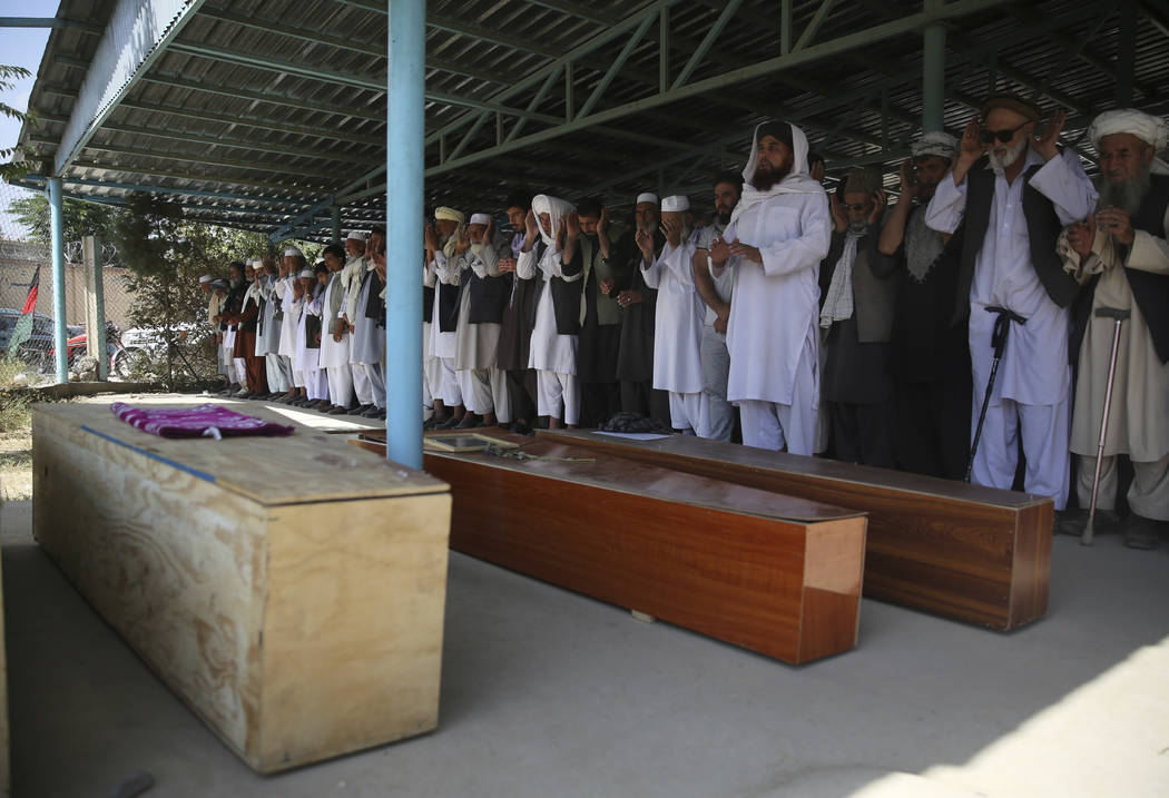 Afghans pray near the coffins of victims of the Dubai City wedding hall bombing during a mass f ...
