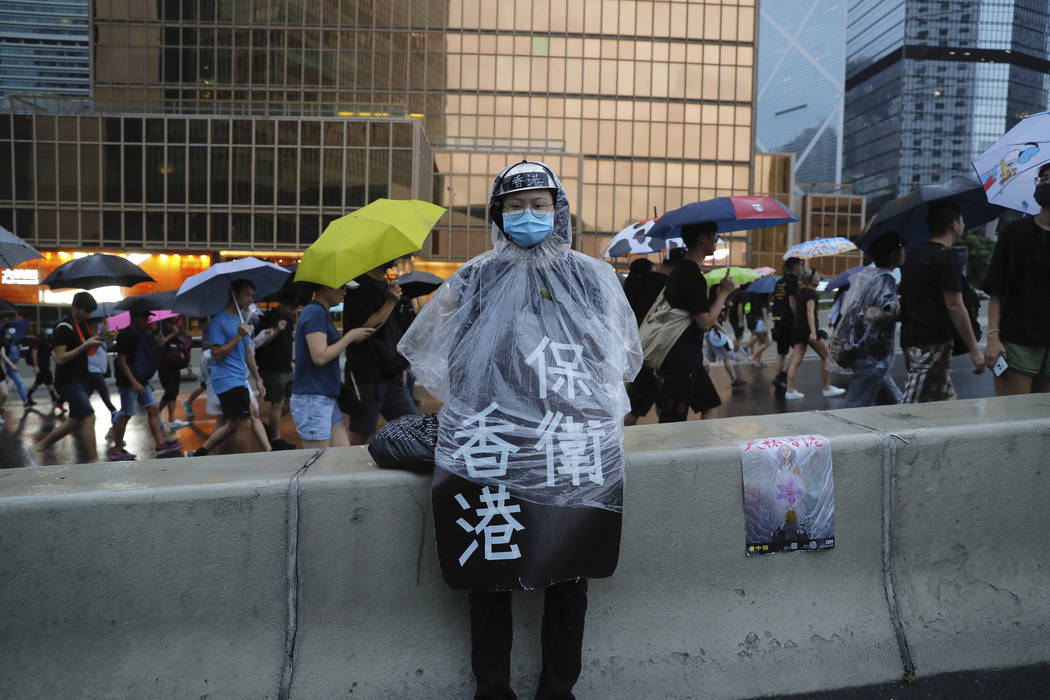 A protester in rain coat wears a sign which reads "Protect Hong Kong" during a march ...