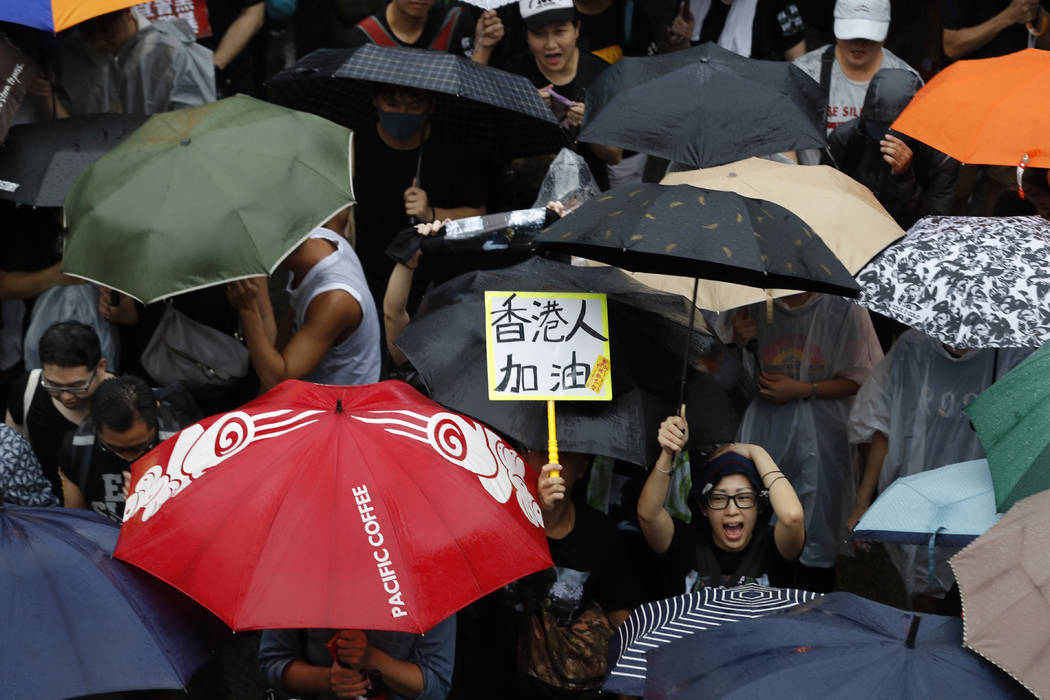 A participant reacts near a sign that reads: "Hong Kong people, Go!" during a protest ...