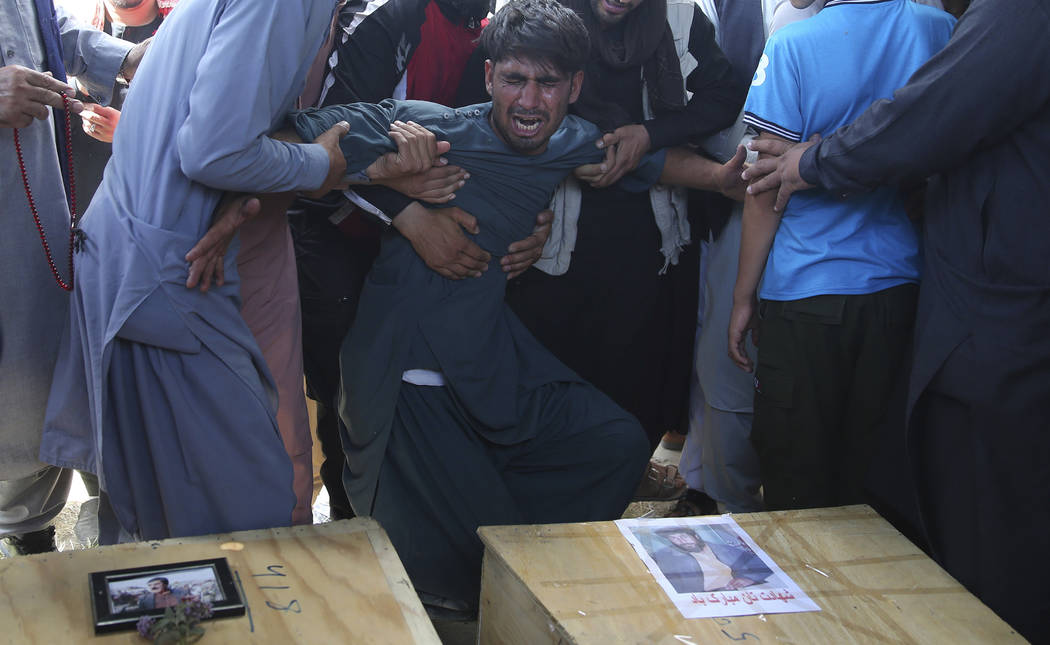 A relative wails near the coffins of victims of the Dubai City wedding hall bombing during a ma ...