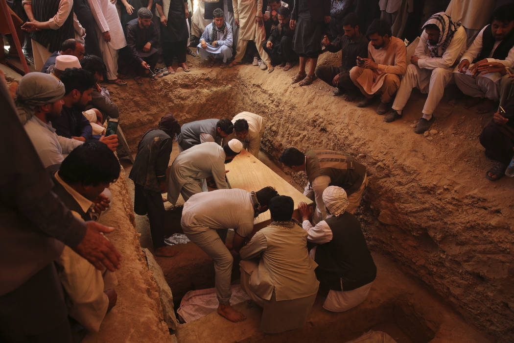 Afghans bury the bodies of victims of the Dubai City wedding hall bombing during a mass funeral ...