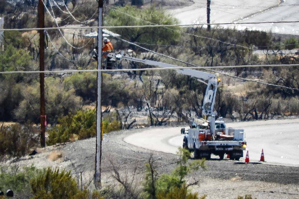 Crews make repairs to power lines in a burned area from the fire at Big Bend of the Colorado St ...