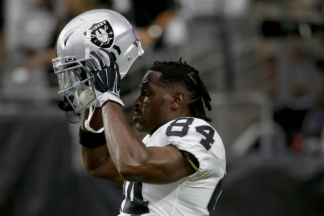 Oakland Raiders wide receiver Antonio Brown (84) puts on his helmet prior to an NFL football ga ...