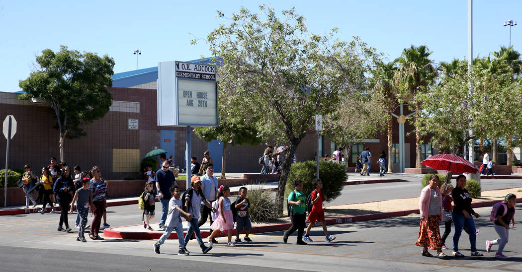 Parents walk their children home from Adcock Elementary School in Las Vegas Tuesday, Aug. 20, 2 ...