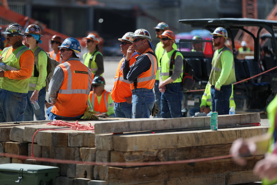 Workers watch as the last high beam is hoisted on top of the future Las Vegas Convention Center ...