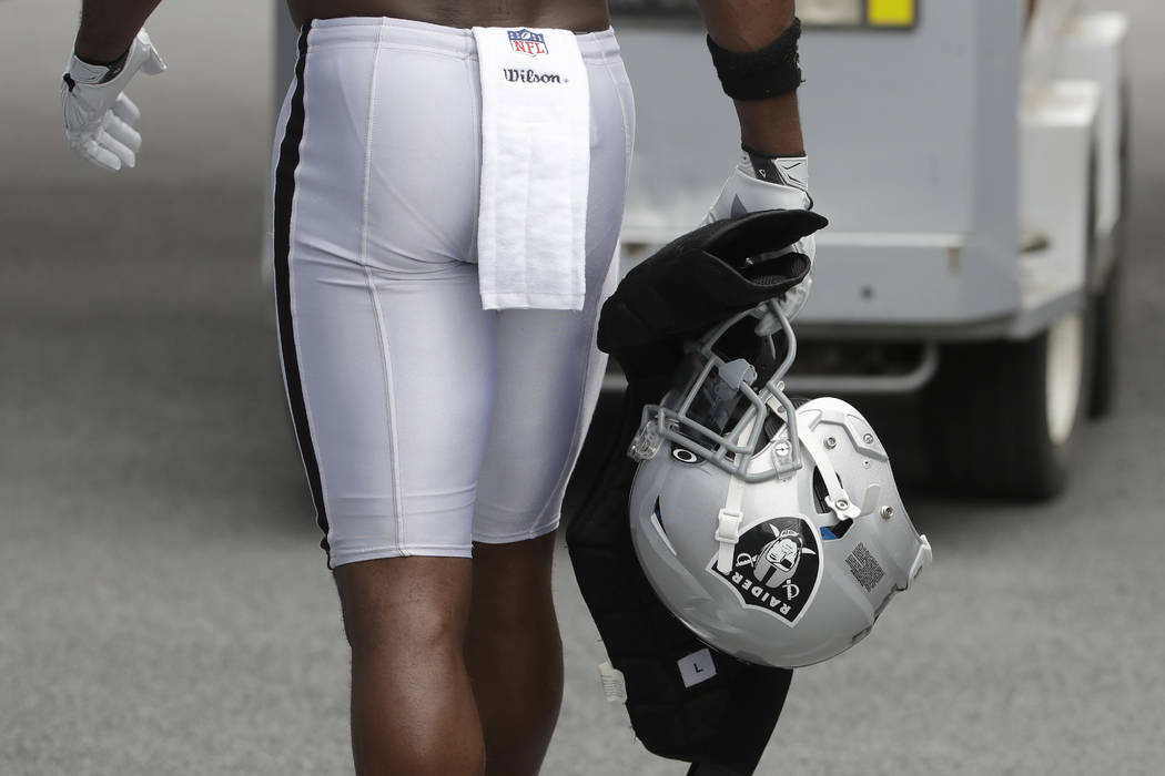 Oakland Raiders' Antonio Brown carries his helmet as he walks off the field after NFL football ...