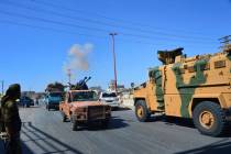 Smoke rises in the background from bombardment around the area as fighters with the Free Syrian ...