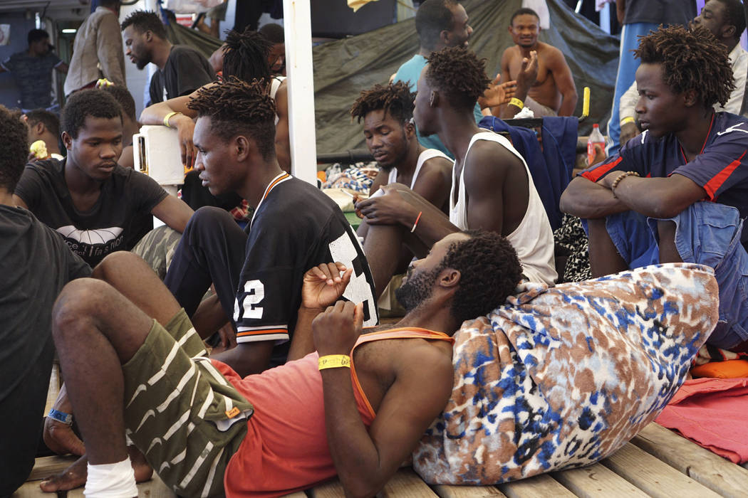 Migrants sit on the deck of the Open Arms vessel in front of island of Lampedusa, southern Ital ...
