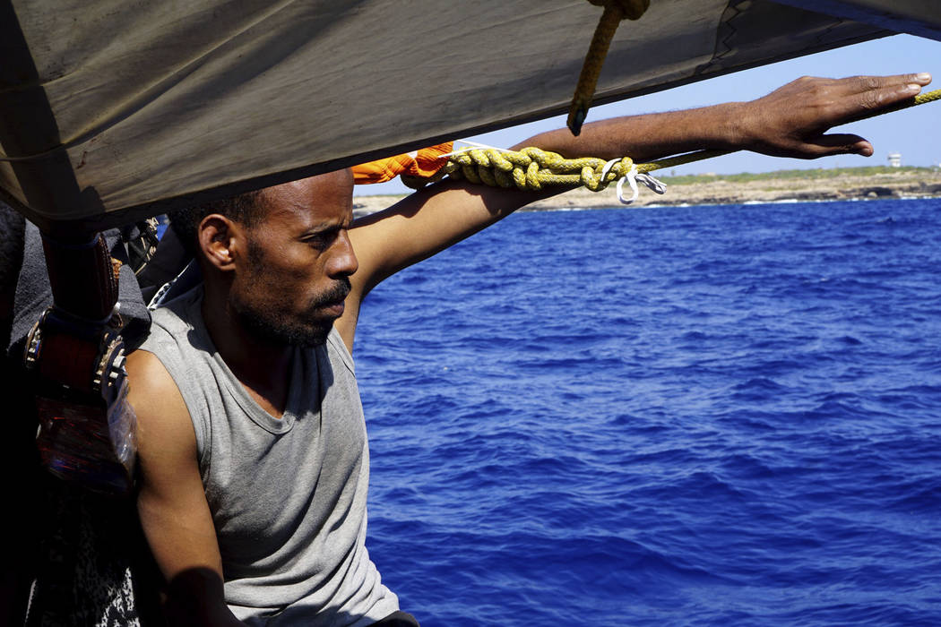 A migrant sits on the deck of the Open Arms vessel in front of island of Lampedusa, southern It ...