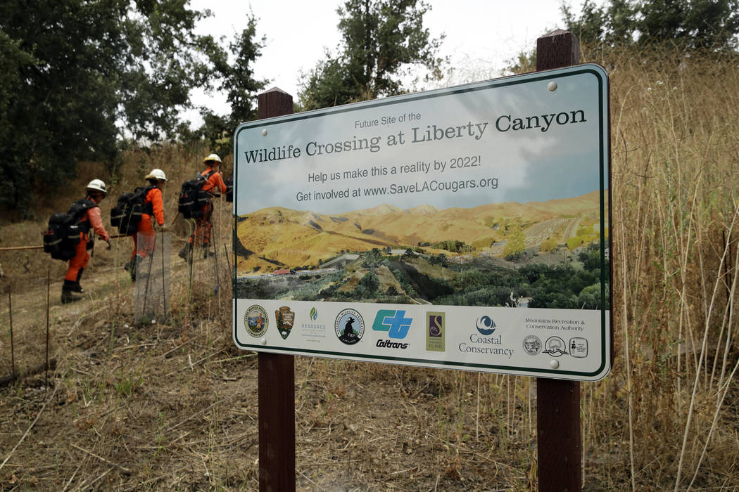 In this July 25, 2019, photo, a fire crew walks past a sign at a proposed site for a wildlife c ...