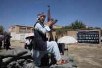 An Afghan volunteer stands guard outside a mosque during a memorial service for the victims of ...