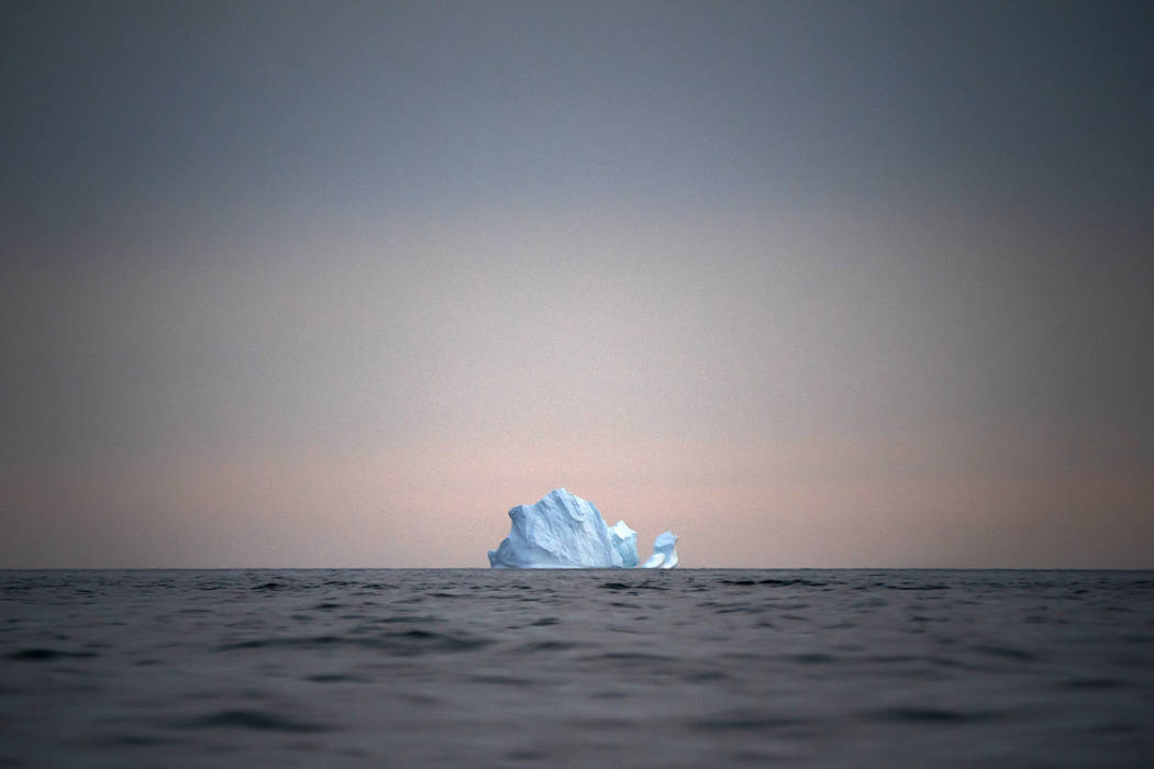 In this Aug. 15, 2019, photo, a large Iceberg floats away as the sun sets near Kulusuk, Greenla ...