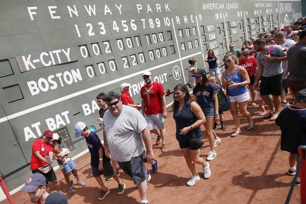 Fans walk on the warning track before a baseball game between the Boston Red Sox and the Kansas ...