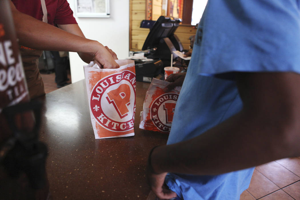 A customer receives his order of the new chicken sandwiches at Popeyes on the corner of Bonanza ...